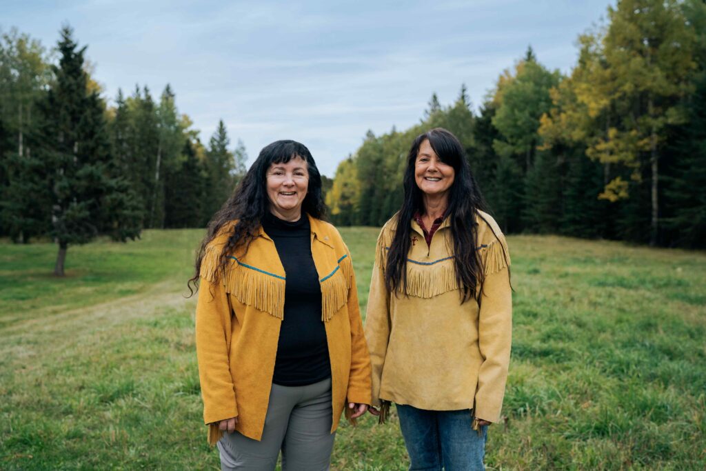 Two people standing side by side in a forest.