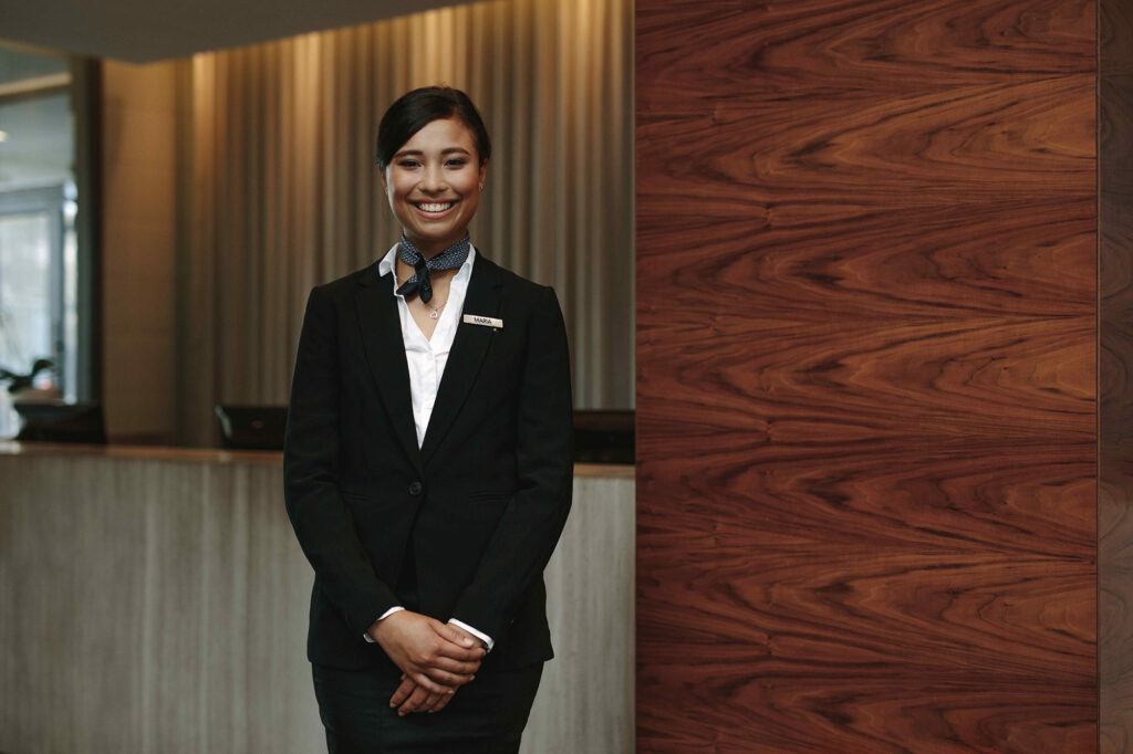 Smiling night auditor in front of a hotel front desk.