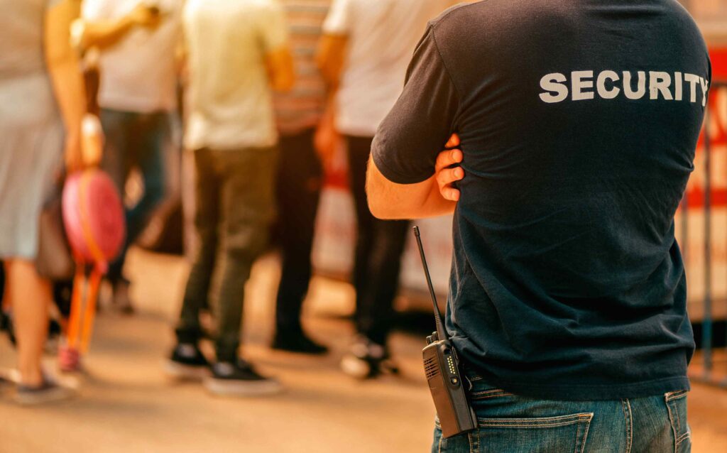 The back of a person providing security at an event, with Security written on the back of their shirt.
