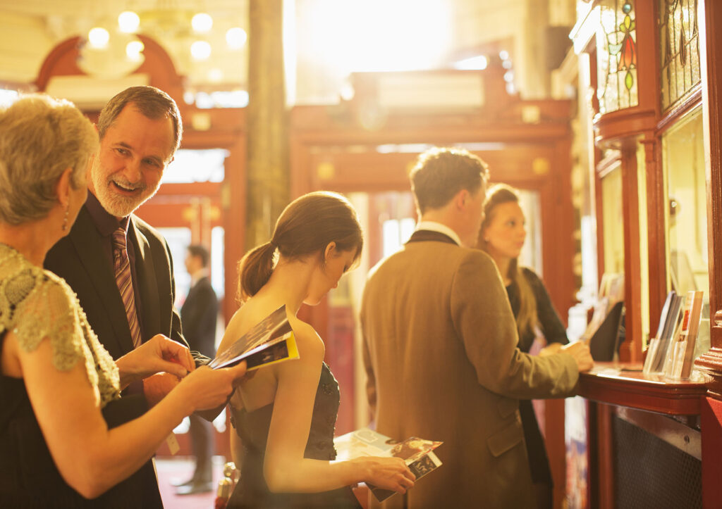 People wearing formal attire standing at the reception area looking at the event agenda. 