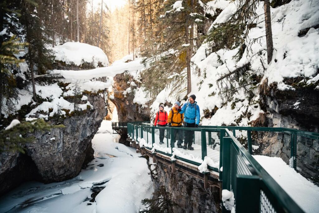 Trois personnes en randonnée d'hiver marchent sur un pont surélevé.