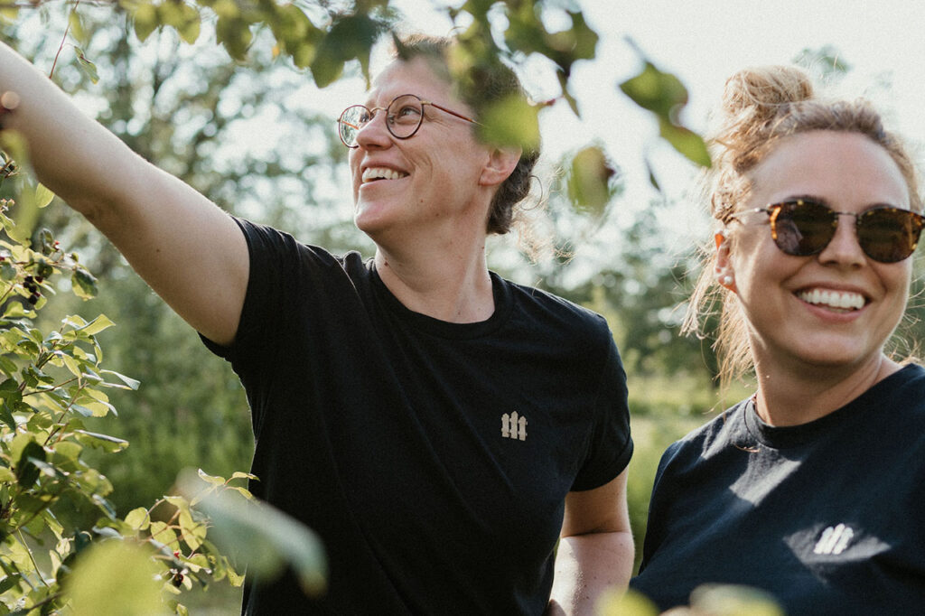 Two people picking grapes while on a vineyard tour.