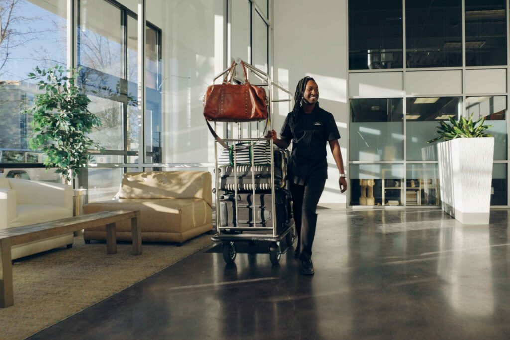 Person guiding a luggage cart through a hotel lobby.