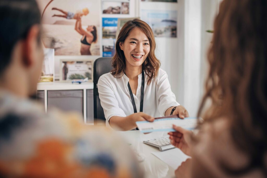 A young travel service agent providing information to two potential travellers.