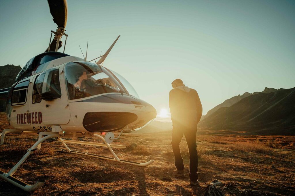 Les mains dans les poches, une personne est debout devant un hélicoptère.