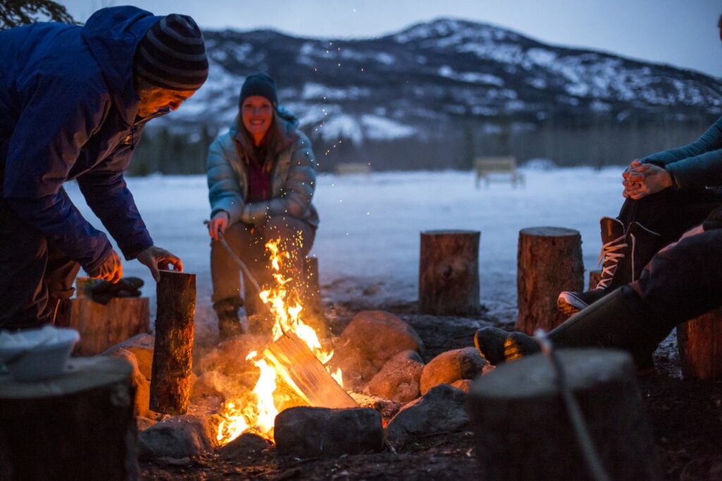Group of travellers enjoying a winter bonfire at dusk.